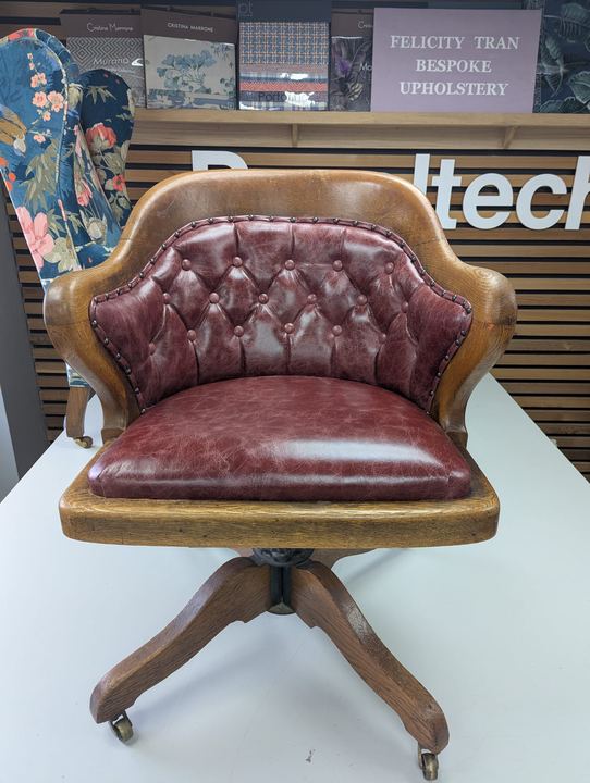 Oak swivel captain's chair with a deep-buttoned oxblood leather back
