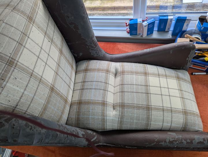 Wing chair before, with peeling vinyl arms and a worn check seat